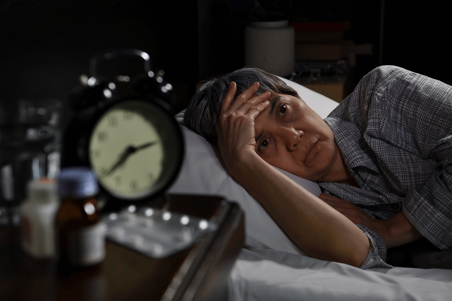 Person sitting on bed at night, depicting sleep difficulties from neuropathy pain